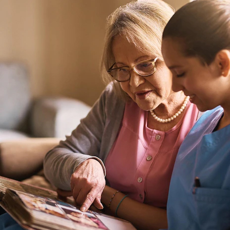 an elderly lady looking through a photo album with a nurse