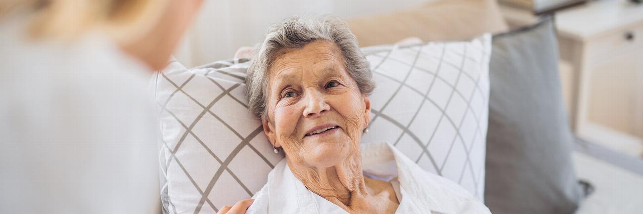 an elderly lady smiling at a nurse as they walk down a corridor